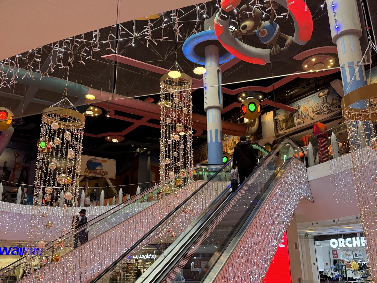 Inside of a shopping centre, showing an escalator and lots of decorations