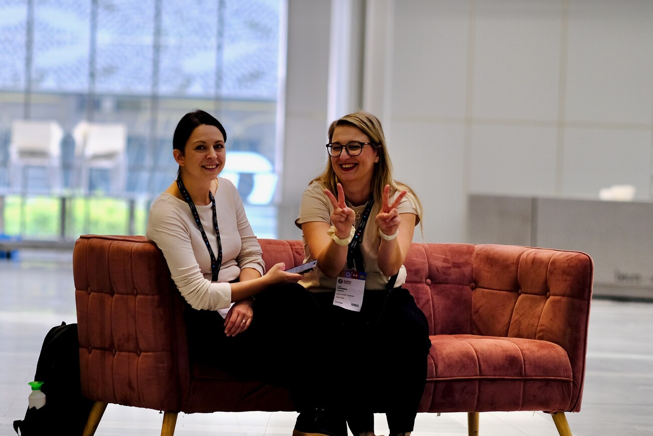 Two people sat on a sofa in the middle of a conference hall